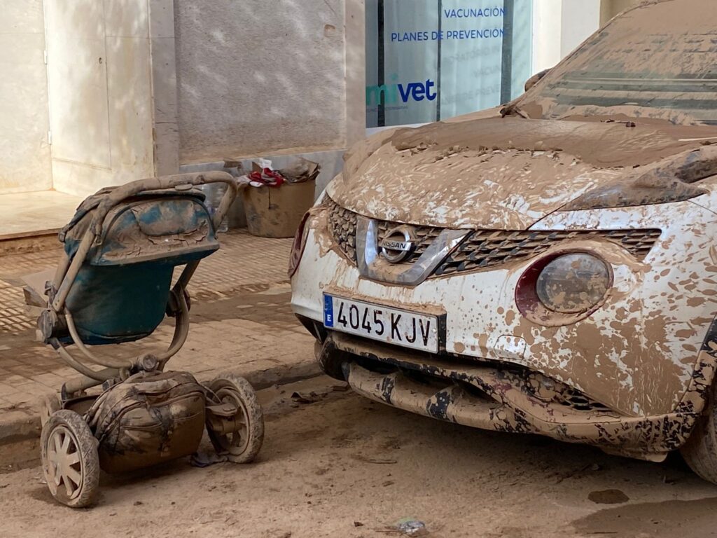 Imagen de la destrucción de la DANA que ha asolado la provincia de Valencia, con un cochecito de bebé y un coche cubiertos de barro.